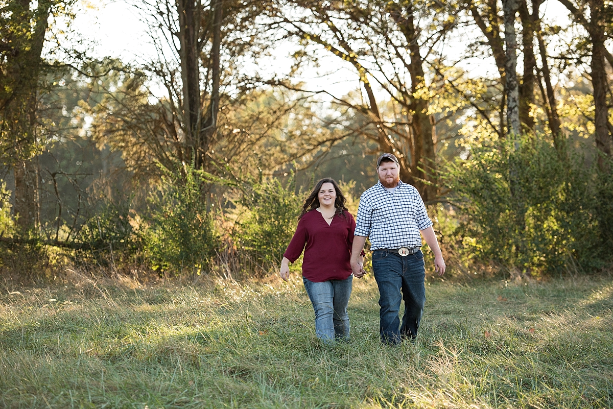 Outdoor country engagement photos of couple walking through field at sunset