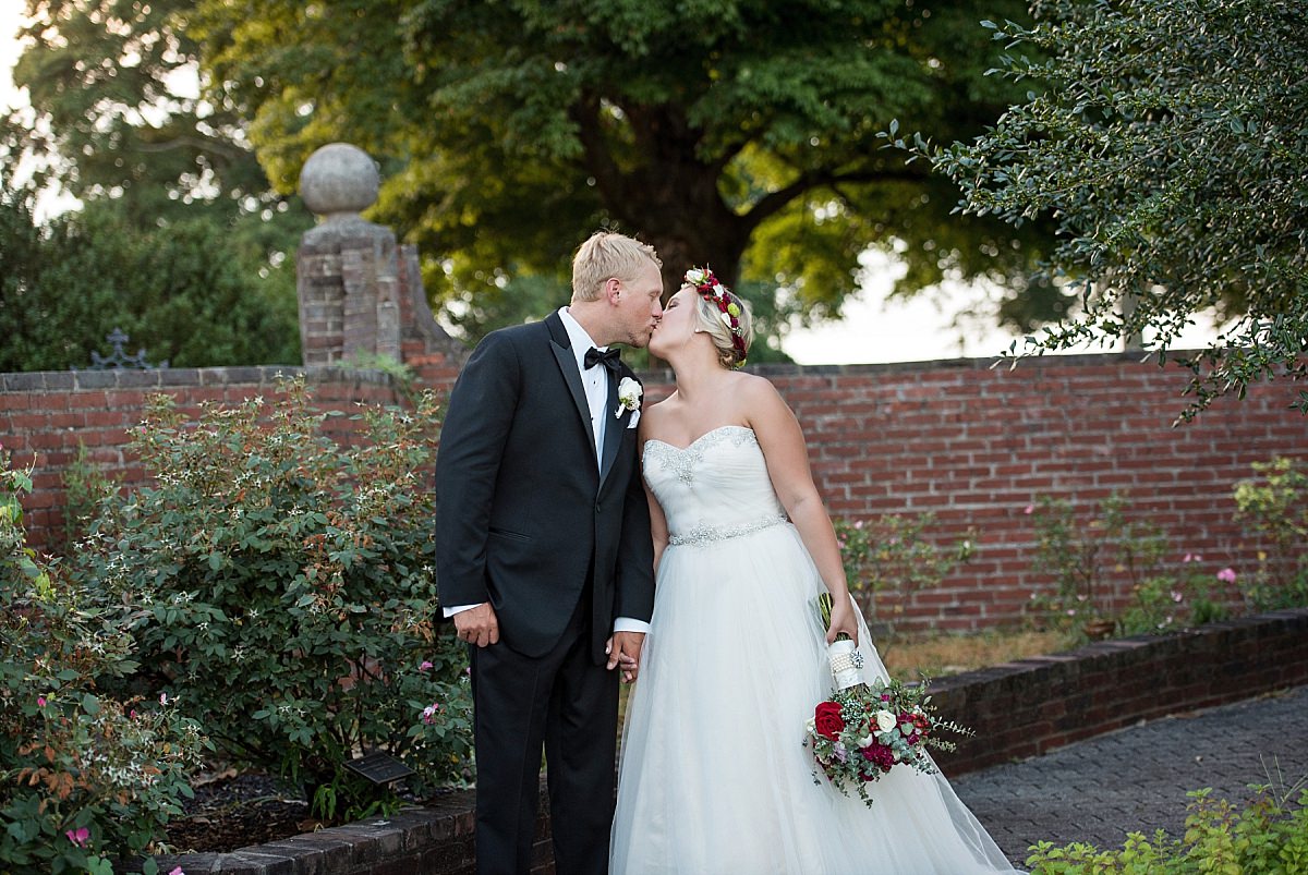 Romantic kiss shared between bride and her husband in side countryard of plantation