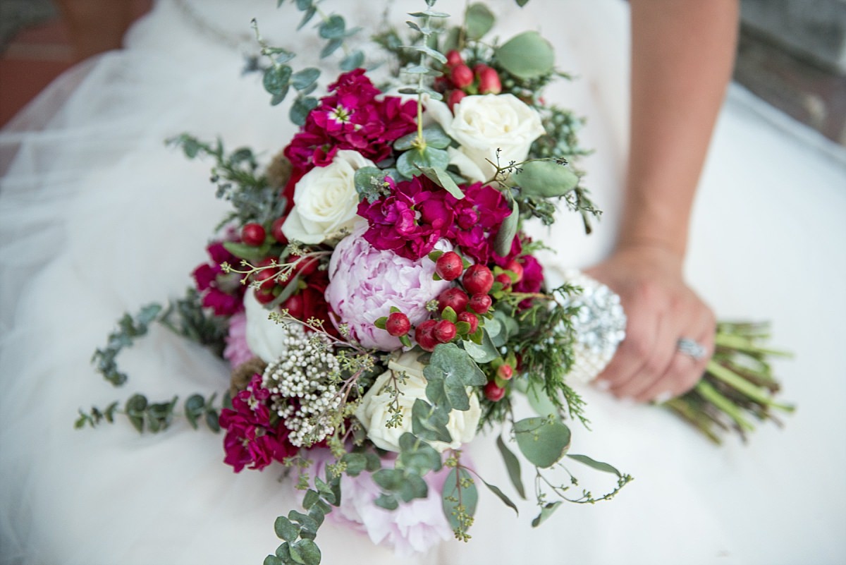 Bride flower bouquet featuring winter tones of reds, pinks, evergreens, and berries