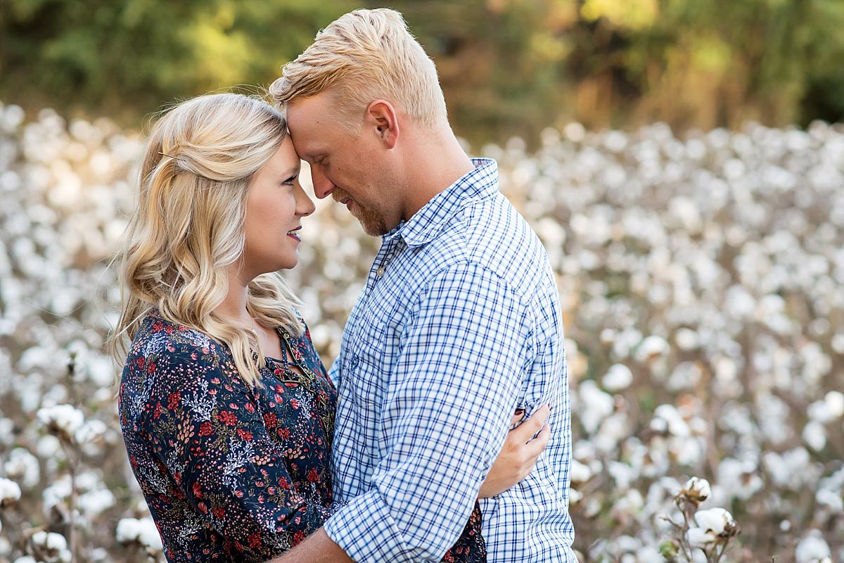 Couple nuzzled together during anniversary photos in cotton field