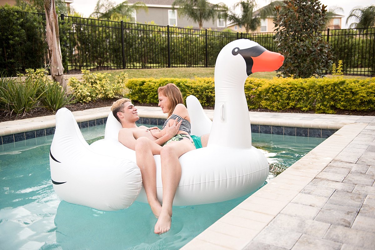 Large inflatable swan with couple laughing and floating in pool