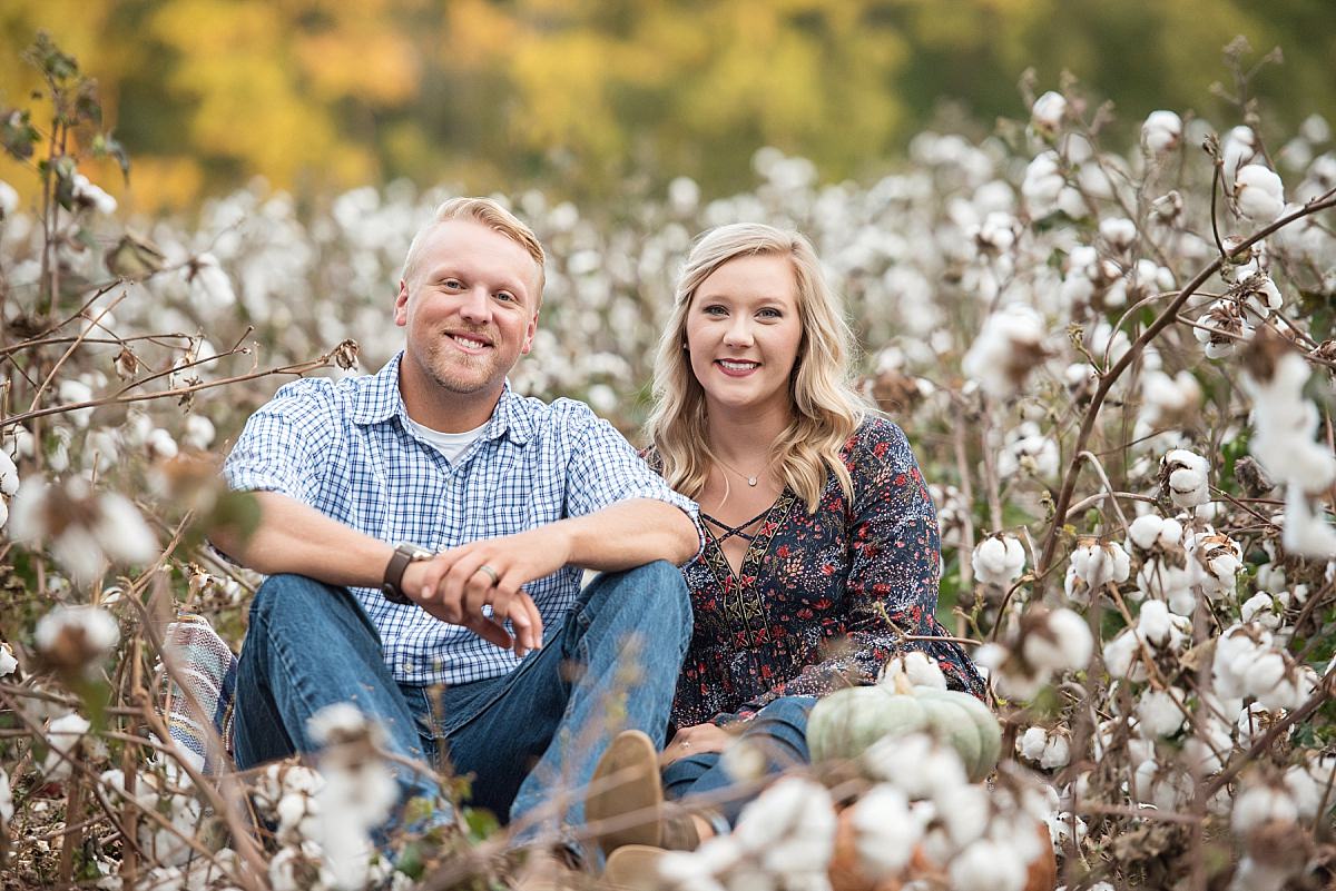 Couple sitting in cotton field during anniversary pictures