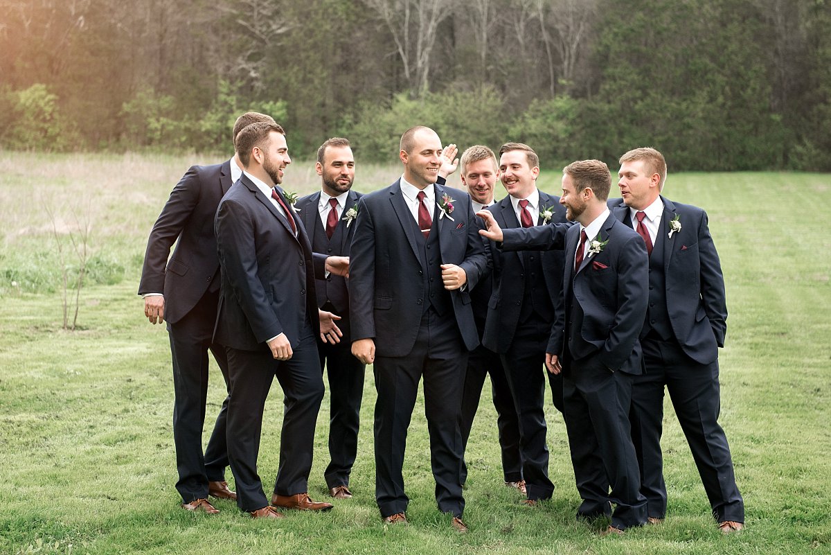 Groom with groomsmen in navy suits and burgundy ties