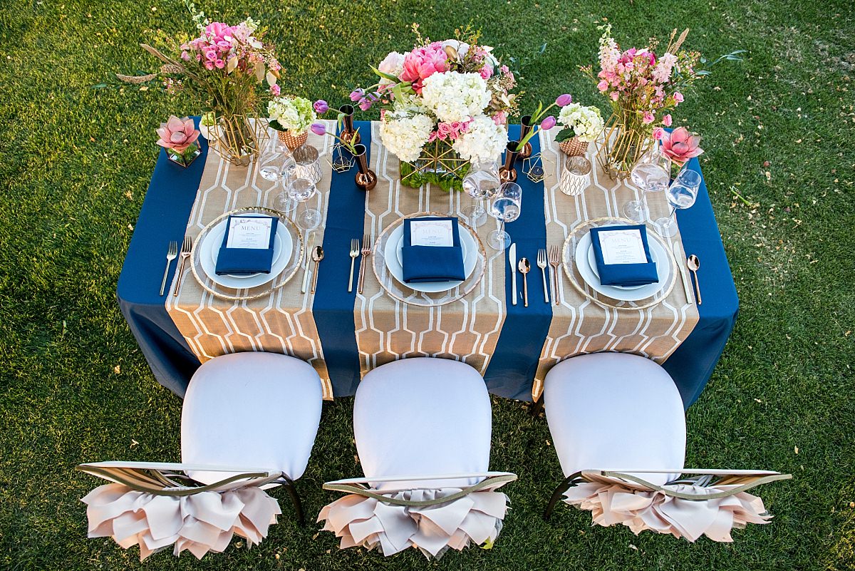 Overhead view of a navy and gold tablescape with luxury chairs and oversized centerpieces